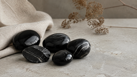 Polerade svarta onyxstenar och bandad onyx på ljus sten med beige linnetyg.