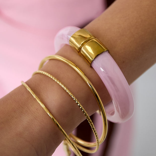 Ljusrosa akrylarmband buret med tunna guldfärgade armband