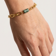 Närbild av fuchsitarmband på handled och vit skjortärm