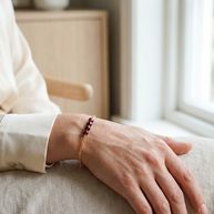 Kvinna som bär nätt armband med granat vid ett fönster