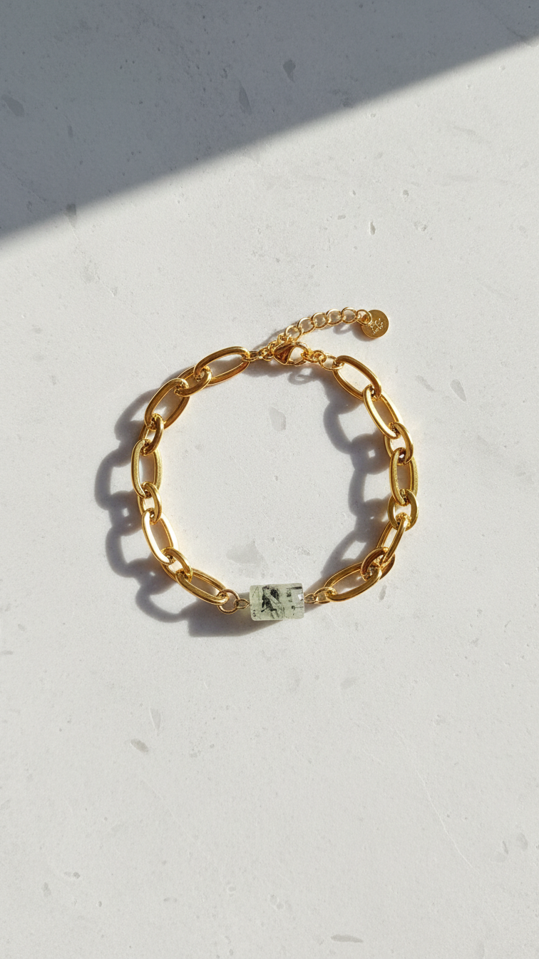 Prehnitarmband utlagt i cirkel på ljus stenplatta