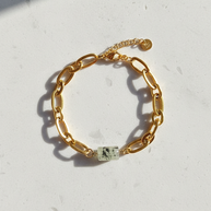 Prehnitarmband utlagt i cirkel på ljus stenplatta