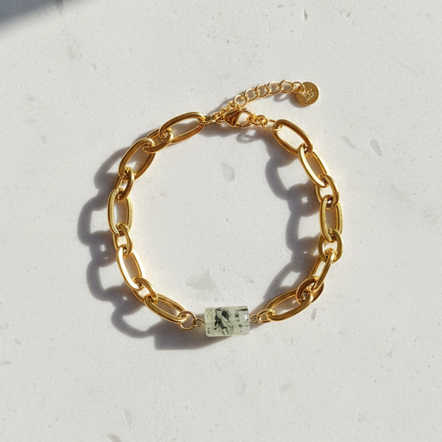 Prehnitarmband utlagt i cirkel på ljus stenplatta