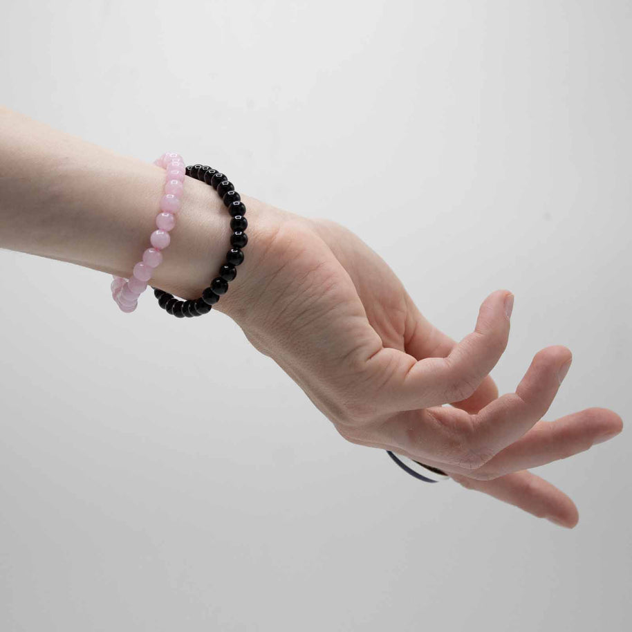 Svart agatarmband och rosa stenarmband visade på två handleder