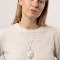 Runt opalithalsband buret mot beige topp