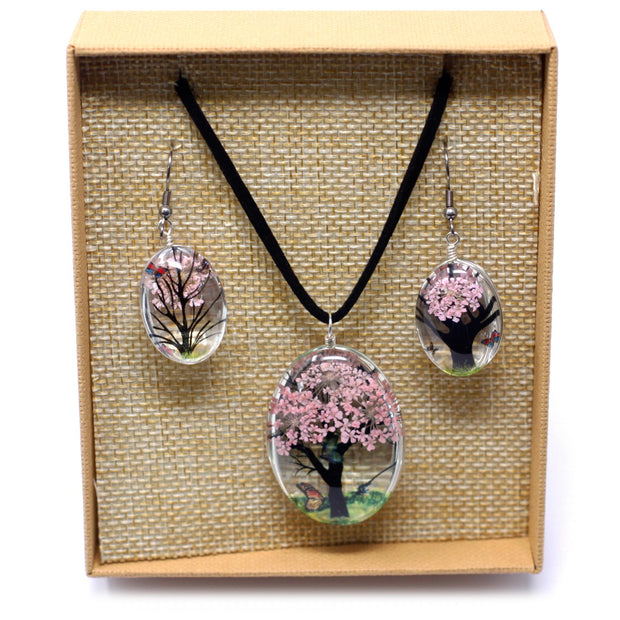 Halsband och örhängen med rosa blommor i öppen ask