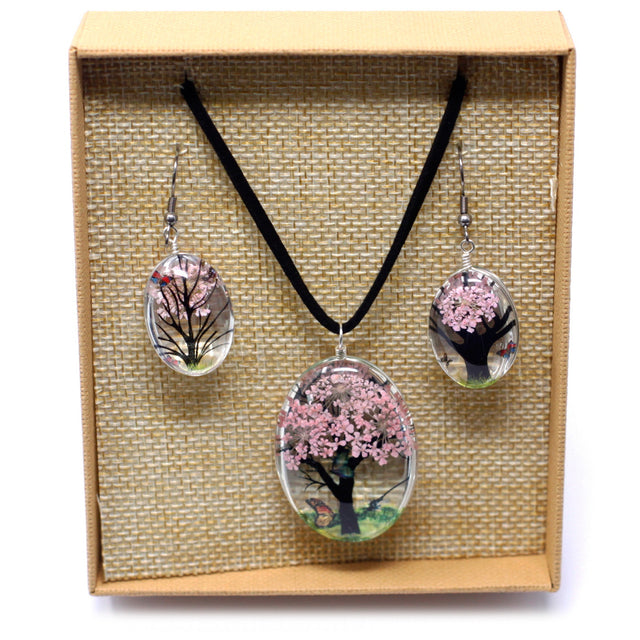 Halsband och örhängen med rosa blommor i öppen ask
