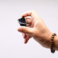 Närbild av rå obsidian mellan fingrar