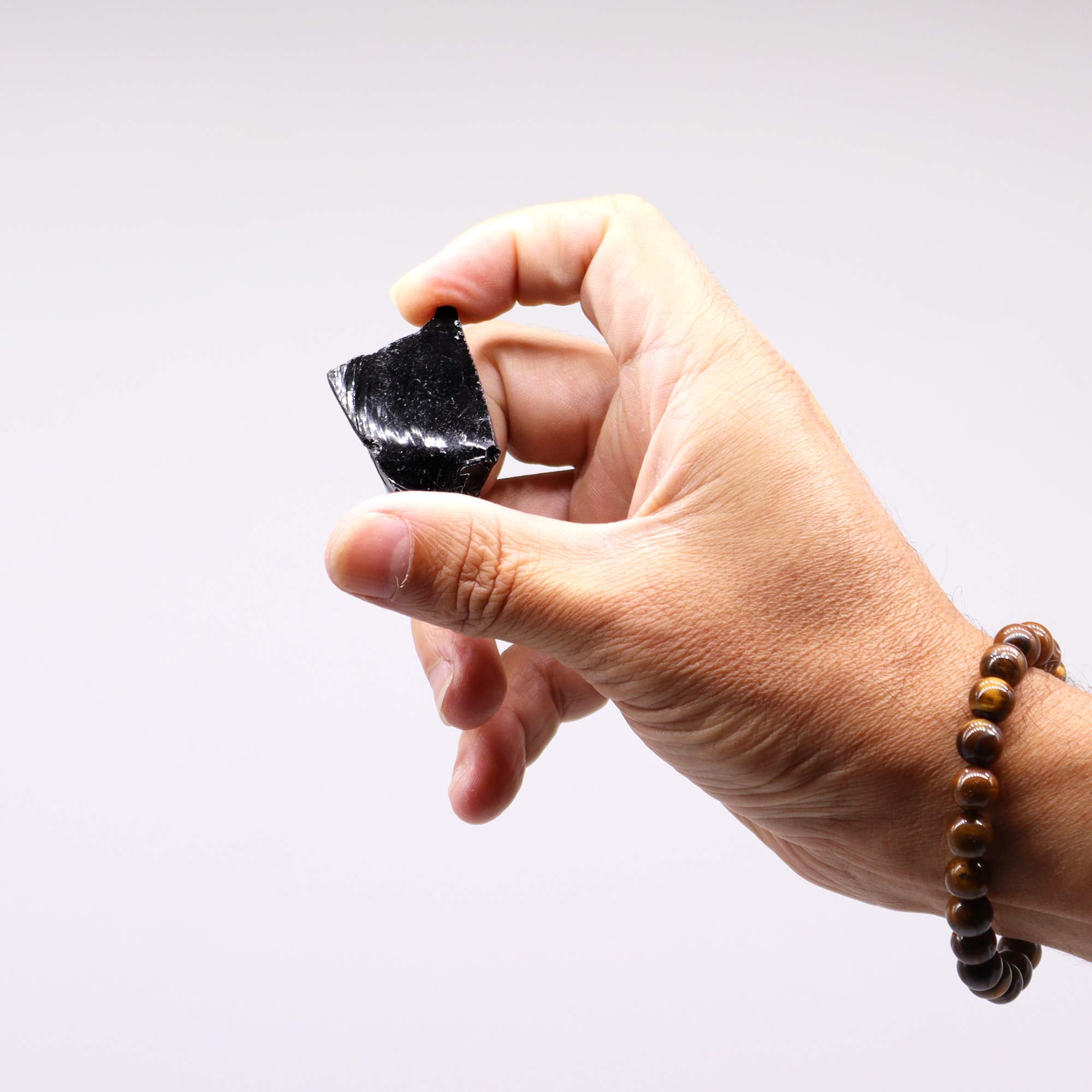 Närbild av rå obsidian mellan fingrar