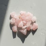 Rå rosenkvarts utlagd på grå yta i solljus